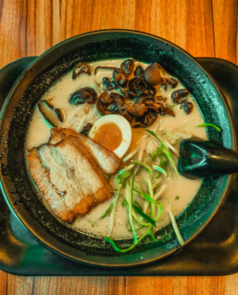 A bowl of creamy ramen browth, noodles, eggs, and meat