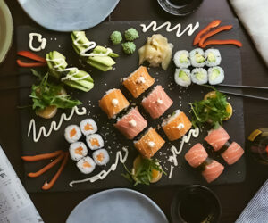 Colorful sushi platter with sauces and chopsticks on the table.