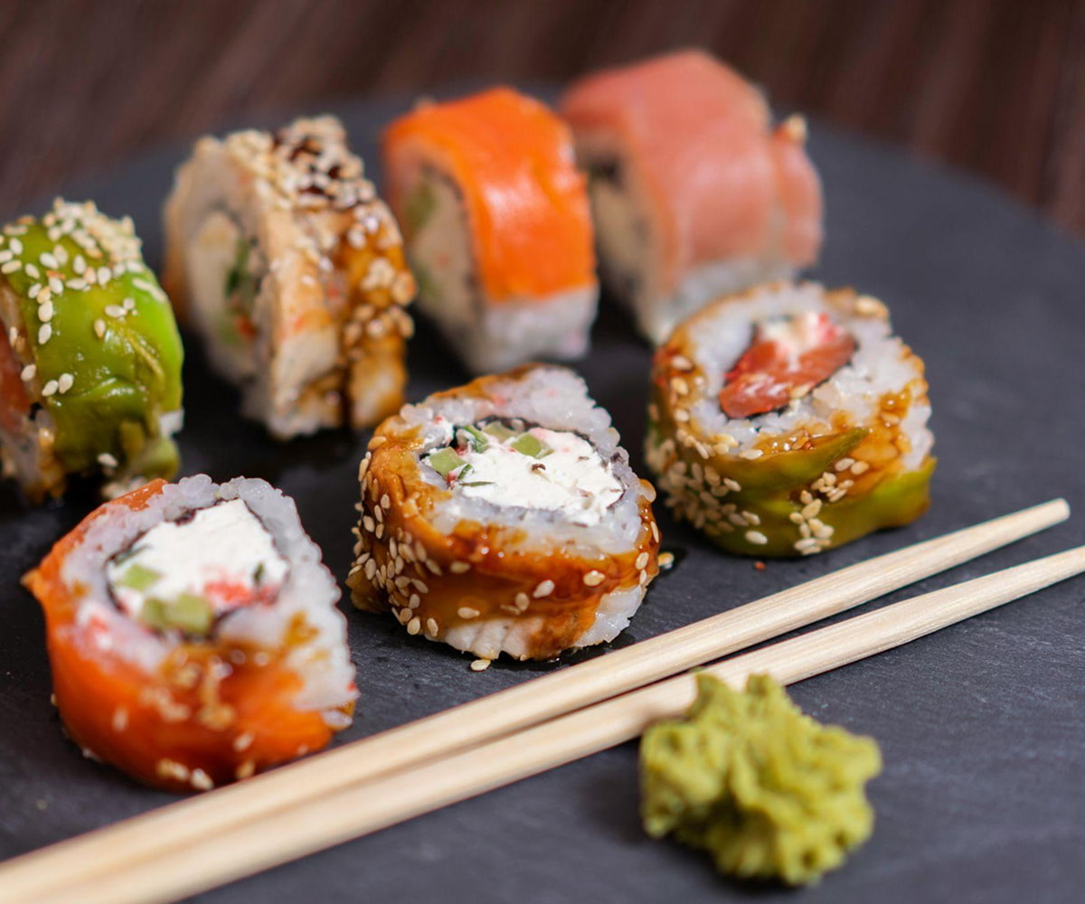 Colorful sushi rolls with sesame seeds and chopsticks.