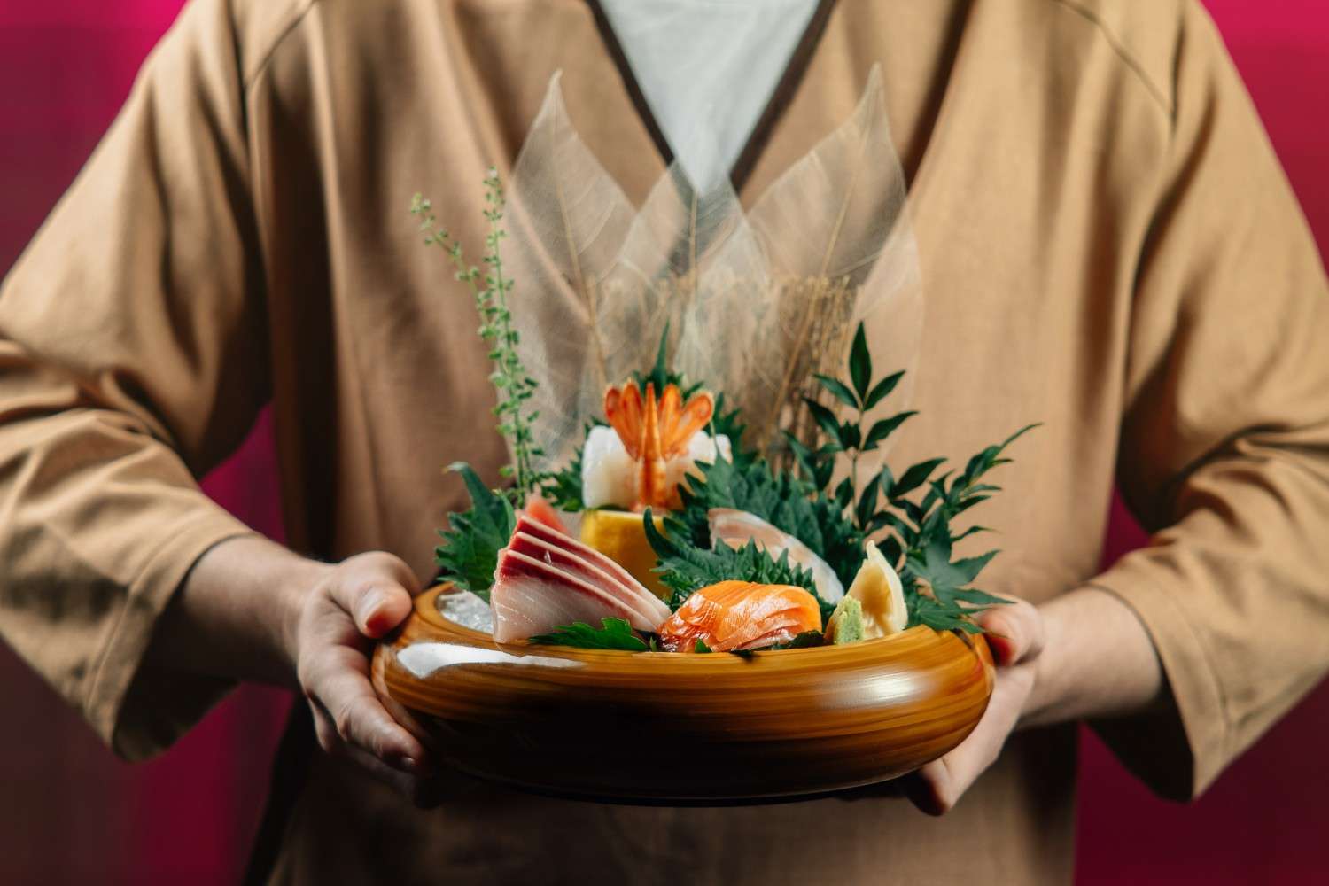 Chef holding a premium sashimi platter with fresh salmon, tuna, shrimp, and garnished Japanese seafood presentation